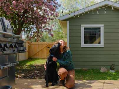 Portrait of woman playing with the dog on the backyard in spring stock photo