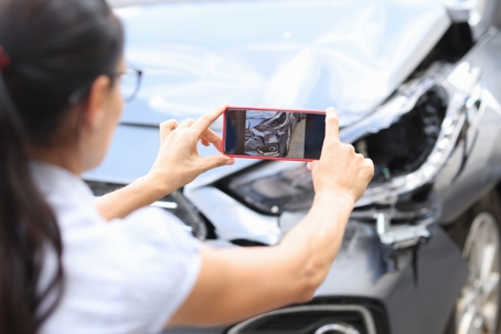 woman taking a photo of a car accident scene